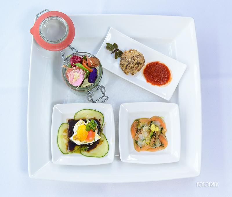 Ein eleganter Vorspeisenteller mit verschiedenen kleinen Gerichten auf einem weißen Teller.