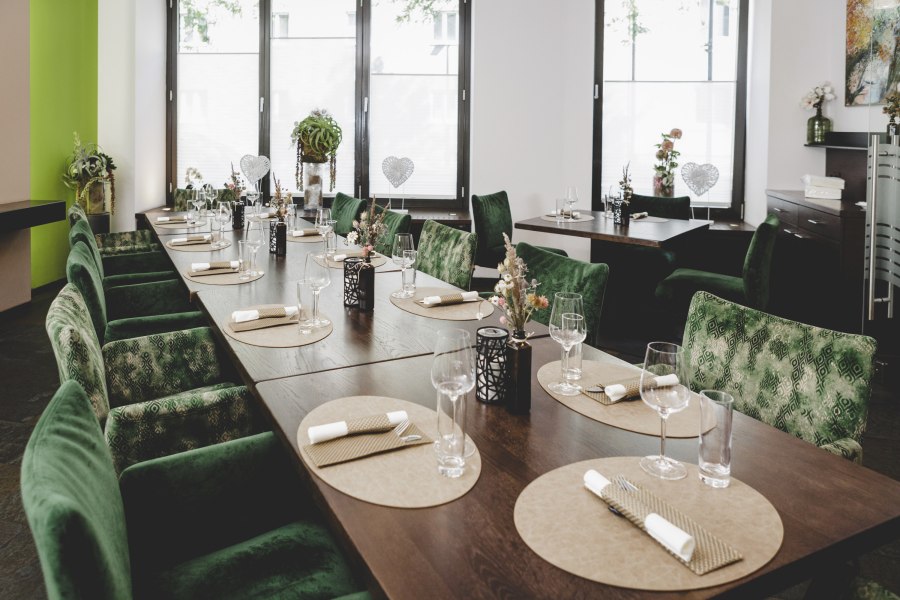 Elegantes Restaurant mit gr&uuml;nen St&uuml;hlen und gedecktem Tisch.