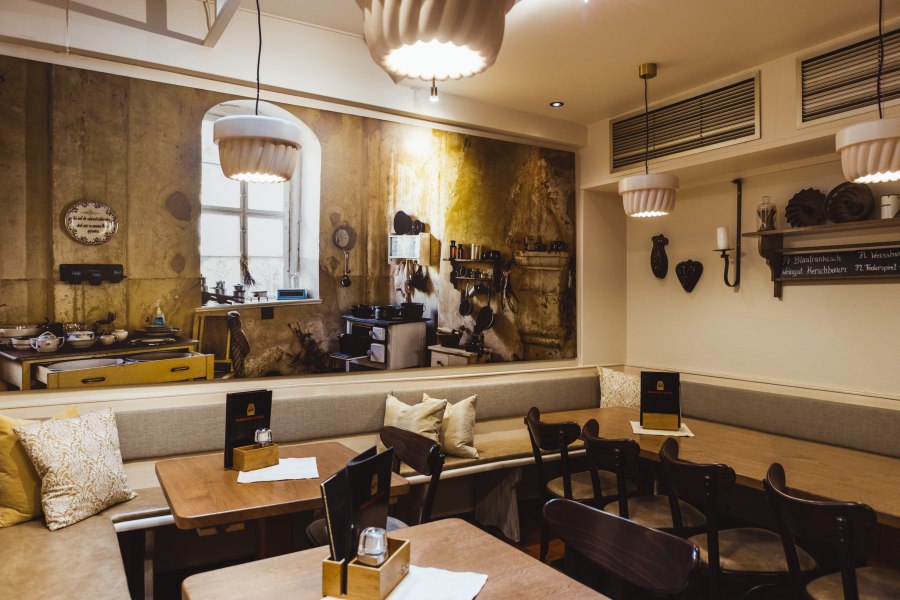 Gem&uuml;tliches Restaurant mit rustikalem Wandbild einer alten K&uuml;che.