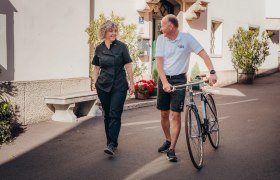 Zwei Personen unterhalten sich, w&auml;hrend einer ein Fahrrad schiebt.