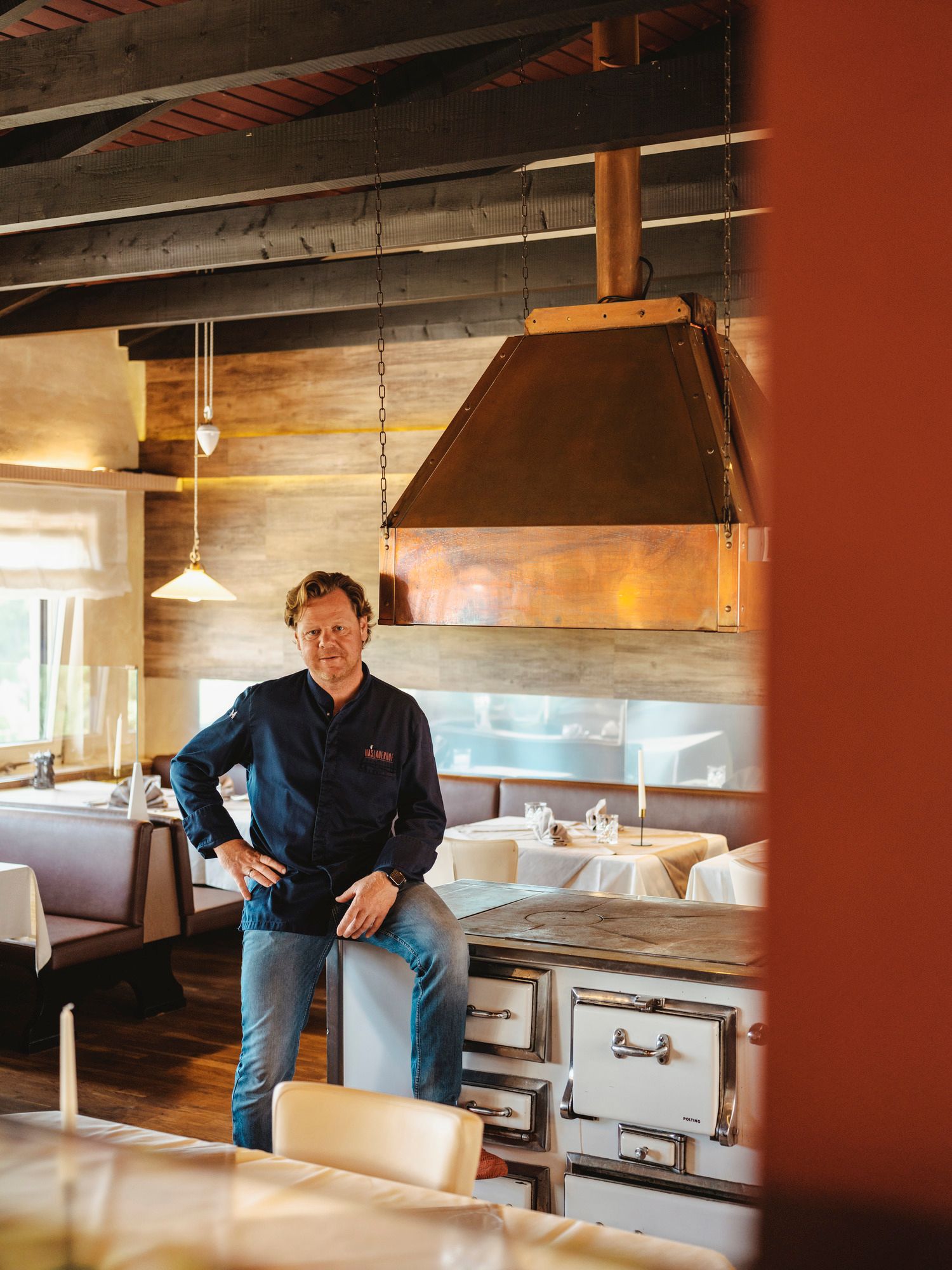 Mann in Restaurant mit rustikalem Holzinterieur und Kupferabzugshaube.