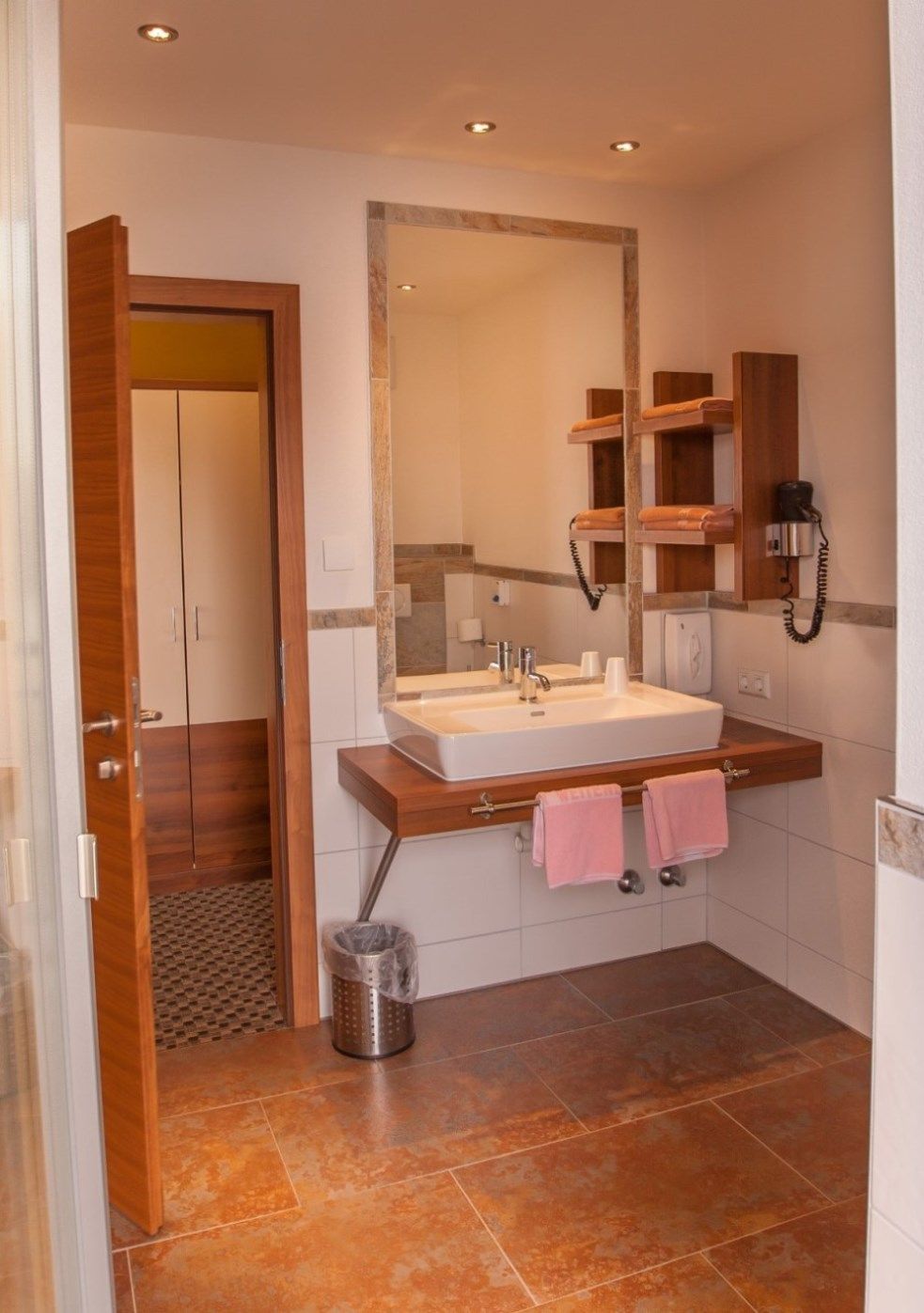 Modernes Badezimmer mit Waschbecken, Spiegel, Handtüchern und Föhn.