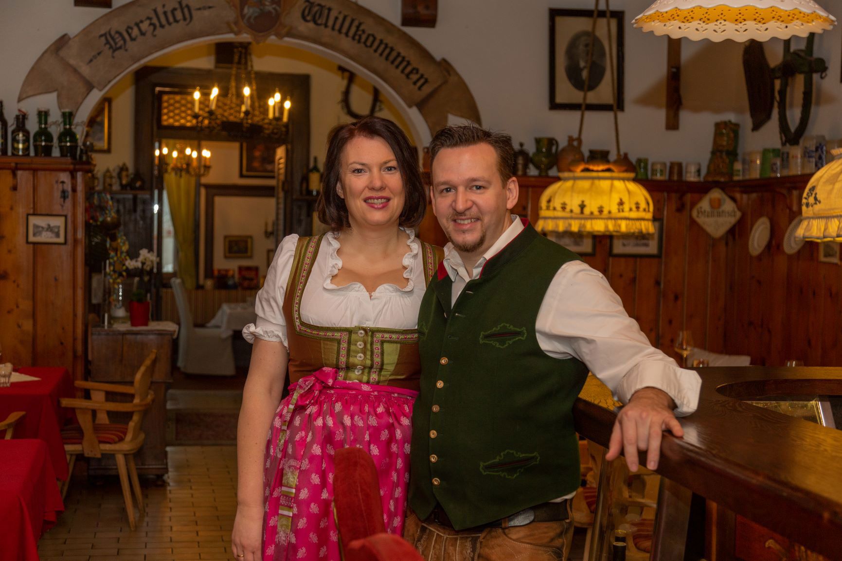 Ein Paar in traditioneller bayerischer Tracht in einem rustikalen Gasthaus.