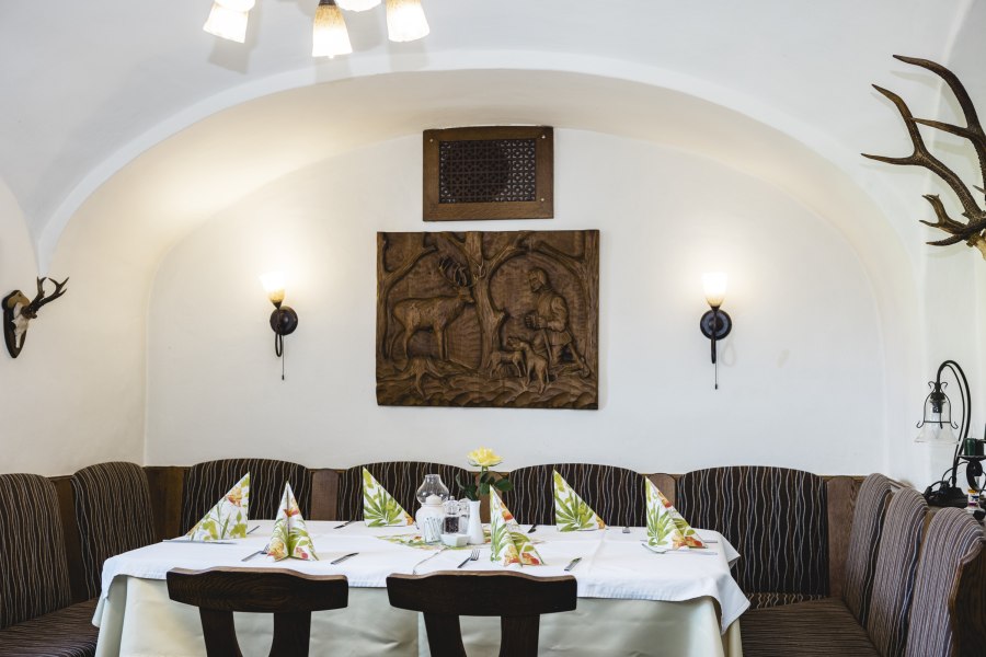 Gem&uuml;tlicher Gastraum mit Holzt&auml;felung und Jagdmotiven an der Wand.