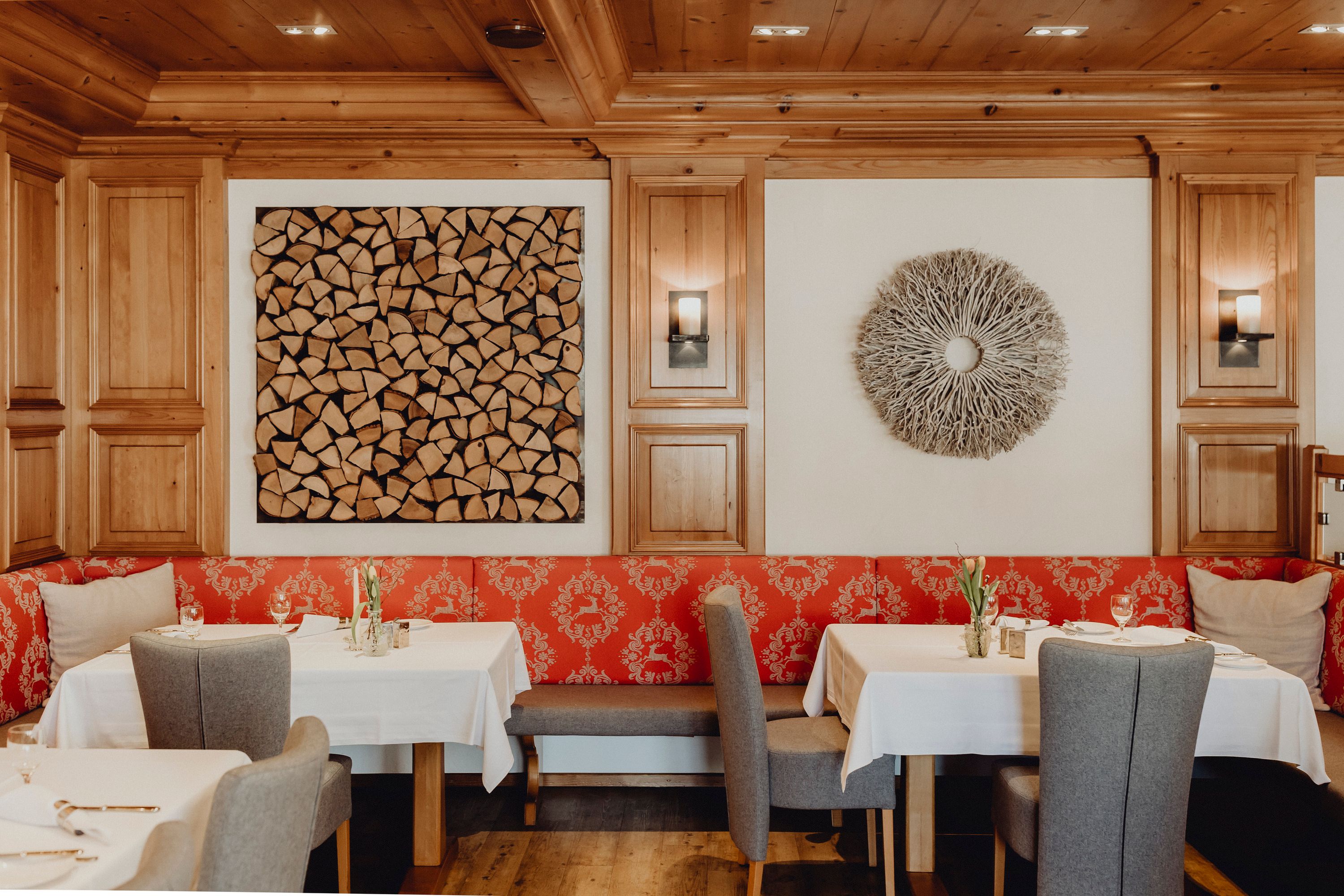 Ein stilvoll eingerichteter Restaurantbereich mit Holzwänden, roten Polstern und dekorativen Wandkunstwerken.