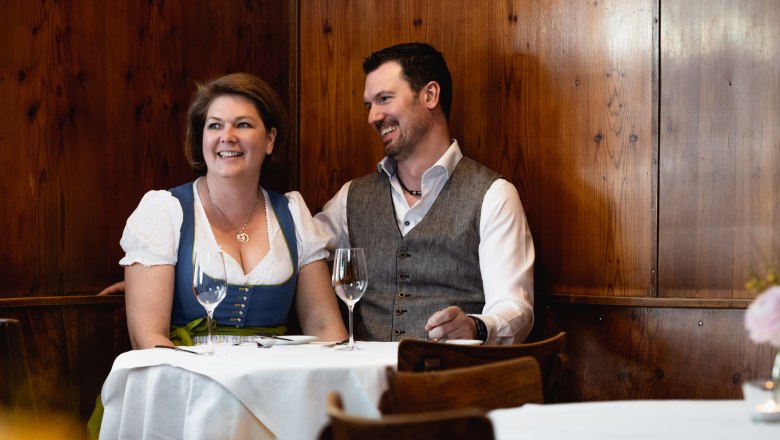 Wirtspaar sitzt in der Stube am Holztisch