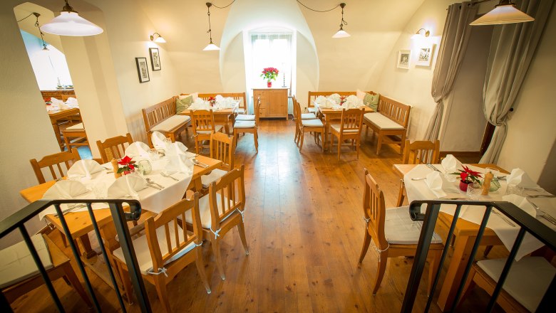 Gem&uuml;tliches Restaurant mit Holzm&ouml;beln und wei&szlig; gedeckten Tischen.