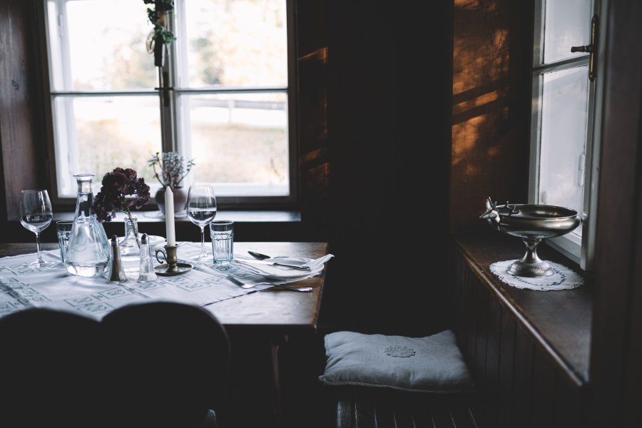 Gem&uuml;tlich gedeckter Tisch in einer rustikalen Stube mit Kerze und Weingl&auml;sern.
