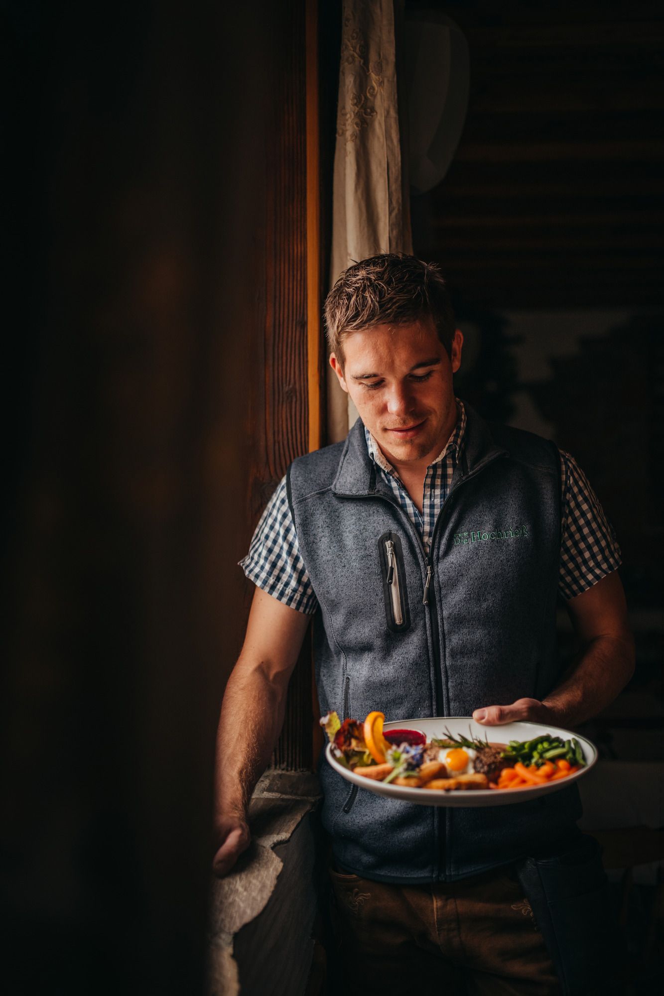 Ein Mann in Tracht hält einen Teller mit Essen in der Hand.