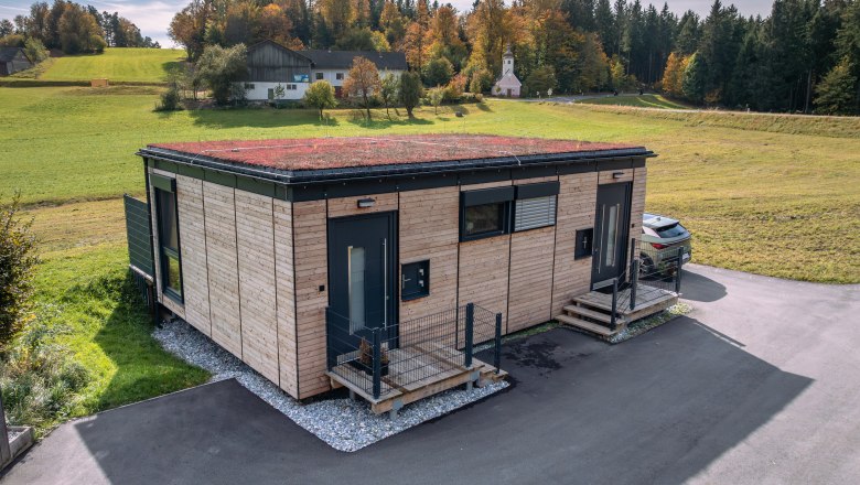 Modernes Holzhaus mit begr&uuml;ntem Dach in l&auml;ndlicher Umgebung.