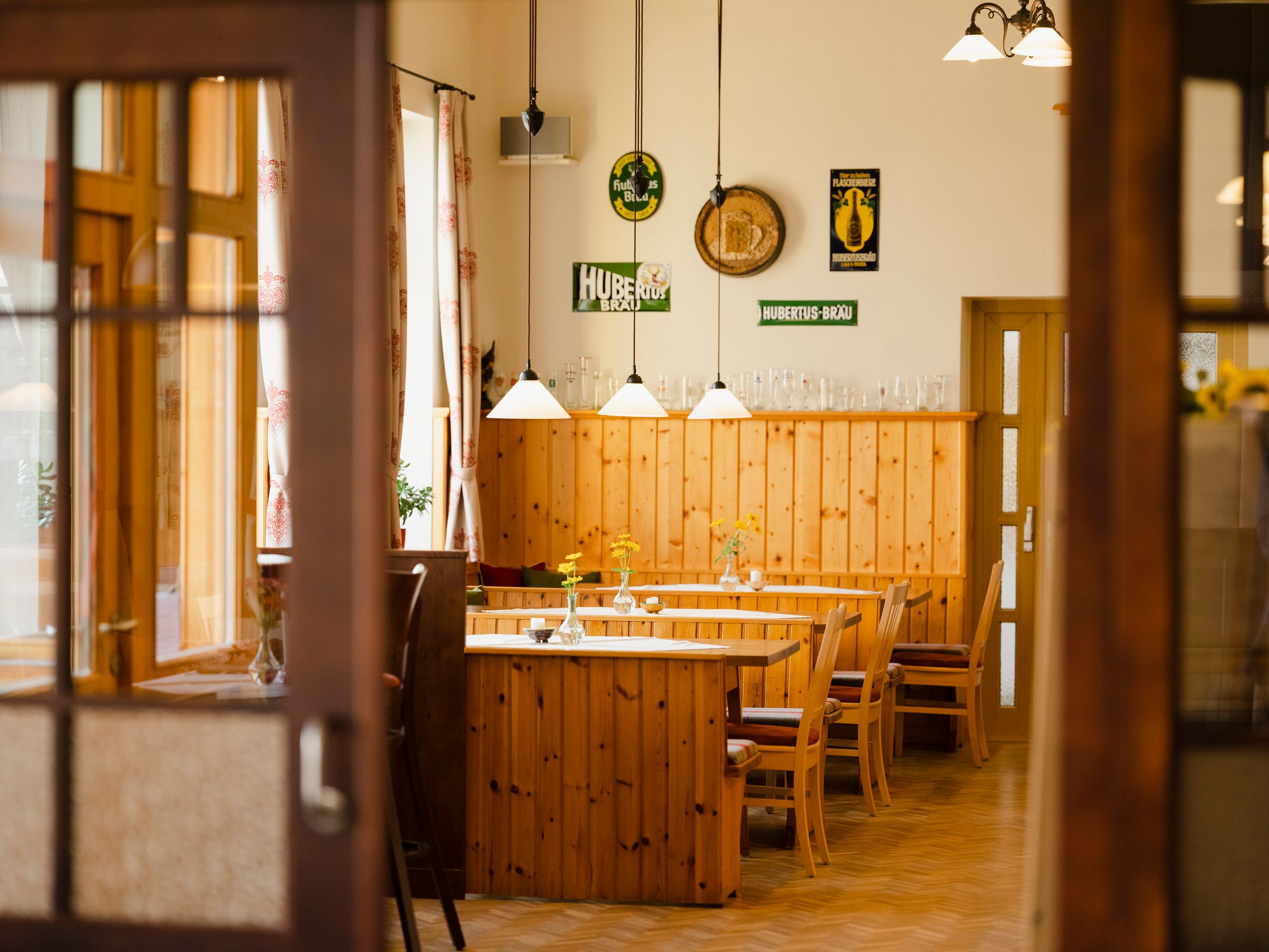 Innenansicht eines traditionellen österreichischen Wirtshauses mit Holzmöbeln und dekorativen Schildern an der Wand.