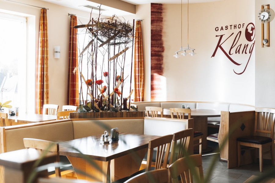 Innenansicht eines Restaurants mit Holzm&ouml;beln und dekorativen Pflanzen.