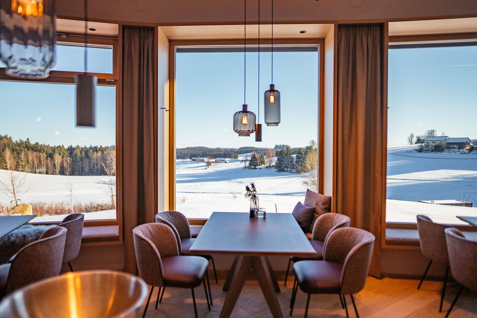 Genießen Sie die atemberaubende Aussicht auf die schneebedeckten Landschaften, während Sie in einem stilvollen Ambiente Platz nehmen. Die großen Fenster lassen das Licht hereinströmen und schaffen eine einladende Atmosphäre, perfekt für eine entspannte Auszeit.