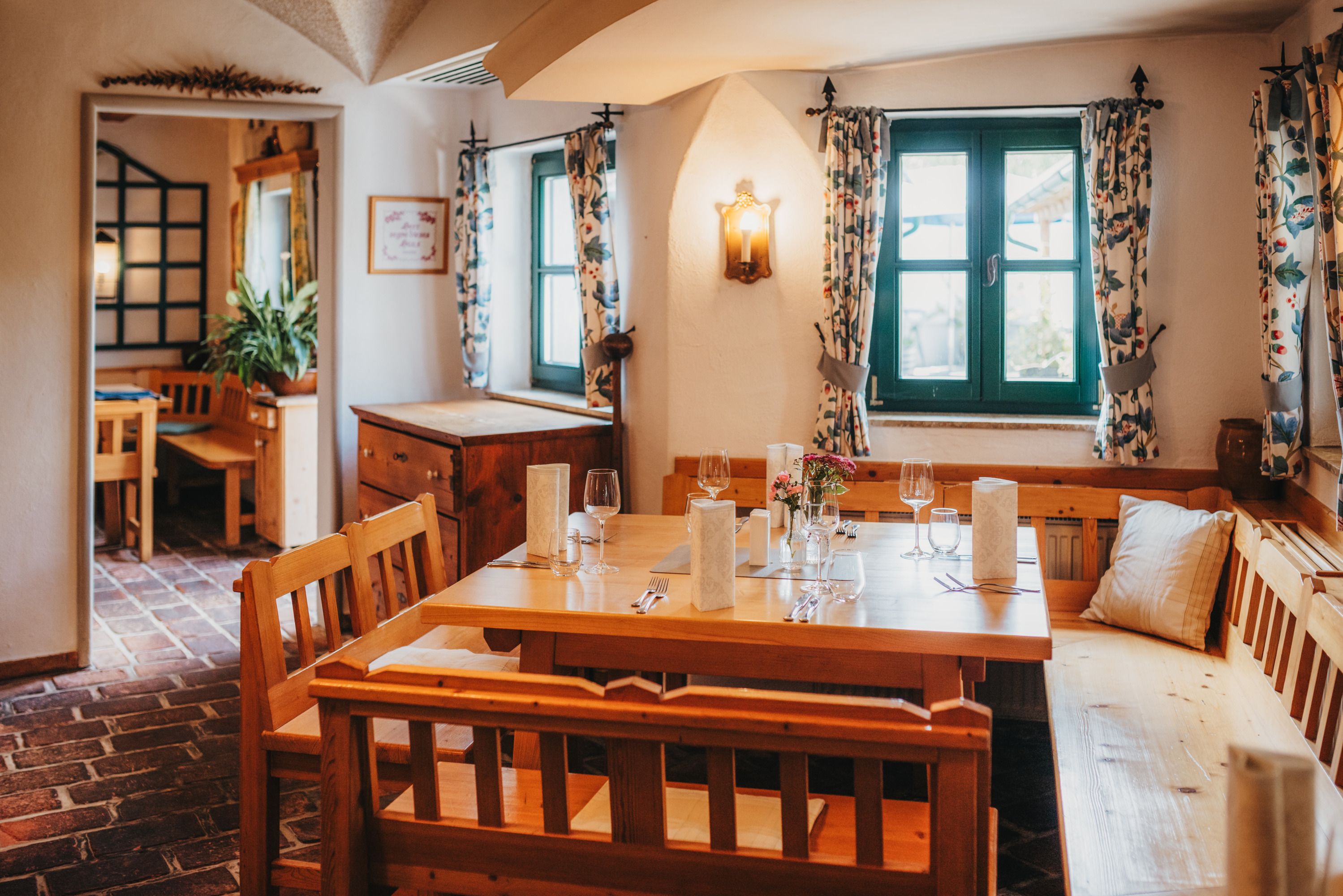 Gemütliche Gaststube mit Holzmöbeln und gedecktem Tisch.