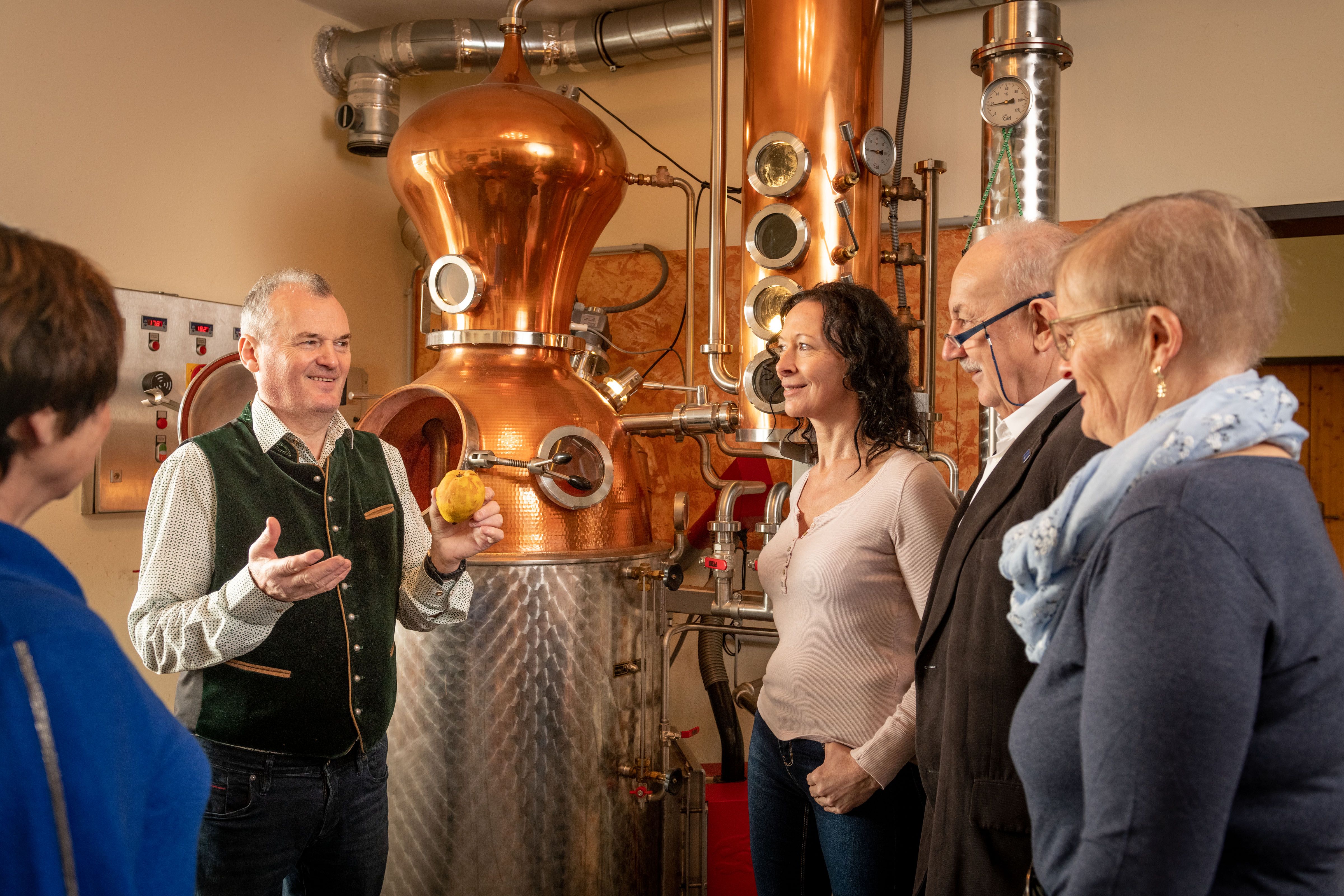 Personen bei einer Führung in einer Brennerei mit Kupferkessel.