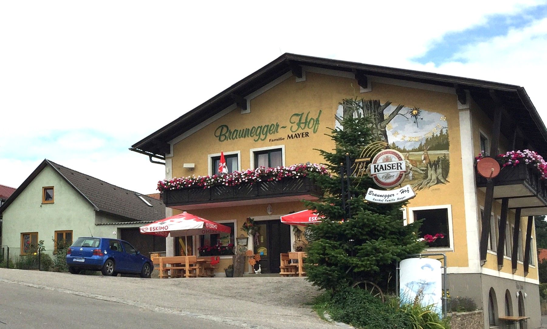 Gasthof Braunegger-Hof with balcony flowers and parasols.