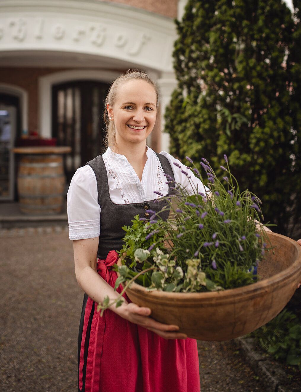 Inmitten der malerischen Landschaft des Mostviertels strahlt die Wirtin Maria Bachler mit einem Korb voller frischer Kräuter. Die sanften Hügel und die üppige Vegetation laden dazu ein, die Aromen der Region zu entdecken und die herzliche Gastfreundschaft zu genießen.