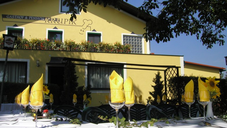 Au&szlig;enansicht des Gasthofs Krupik mit gedecktem Tisch im Vordergrund.