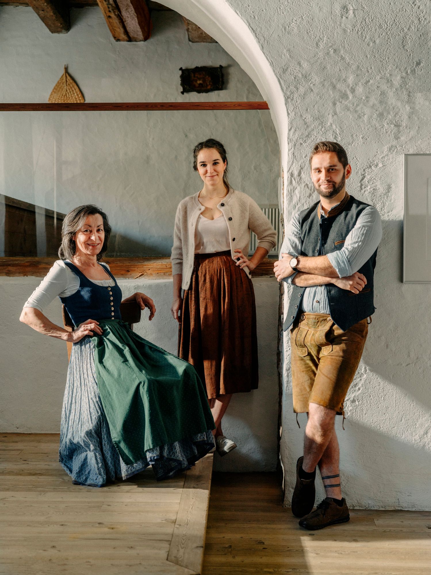 Drei Personen in traditioneller Kleidung in einem rustikalen Raum.