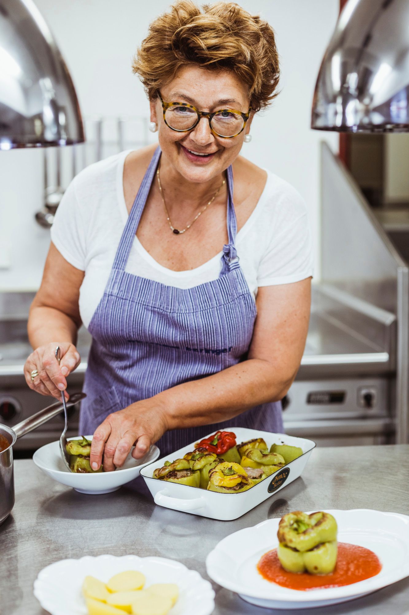 Eine Frau in einer Küche bereitet gefüllte Paprika zu.