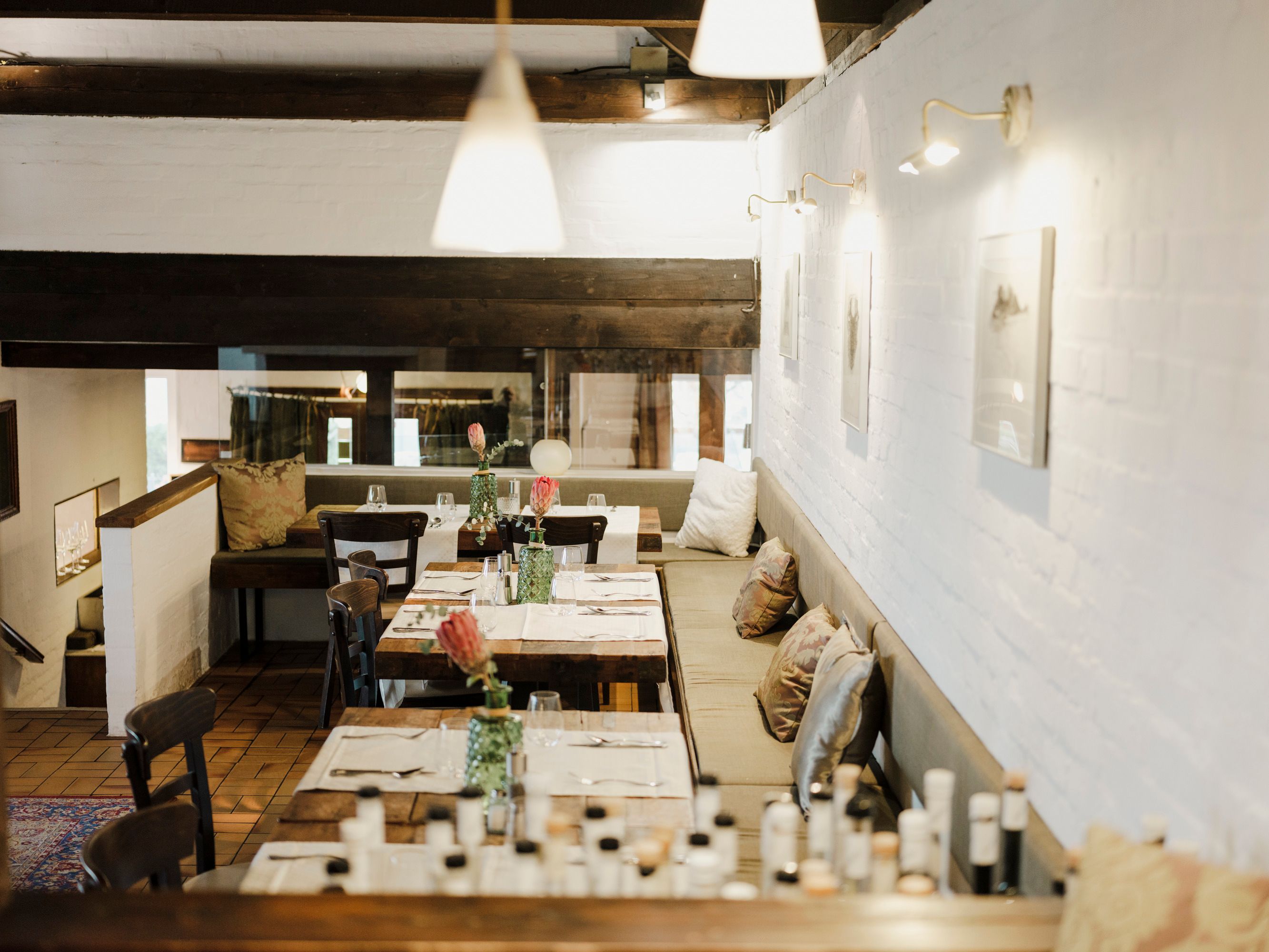 Gemütliches Restaurant mit Holztischen, Kissen und dezenter Beleuchtung.