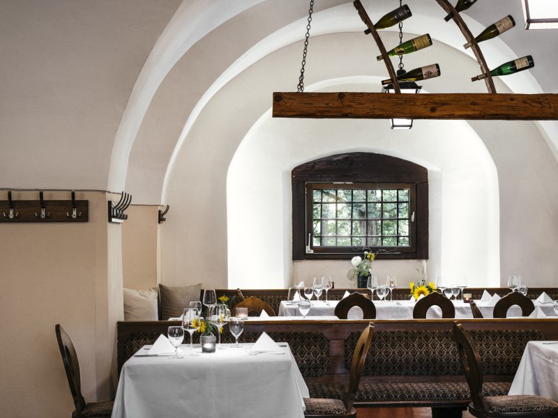 Elegantes Restaurant mit gewölbten Decken, gedeckten Tischen und Weinflaschen-Dekoration.