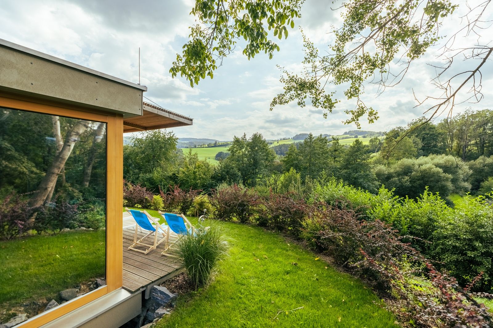 Garten mit Liegestühlen und Blick auf eine grüne Landschaft.