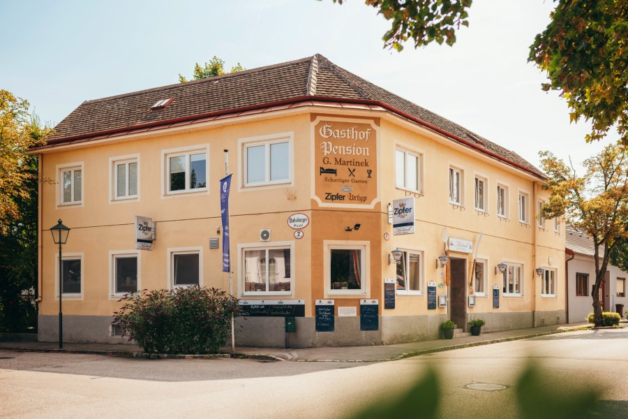 Ein gelbes zweistöckiges Gebäude mit der Aufschrift 'Gasthof Pension G. Martinek'.