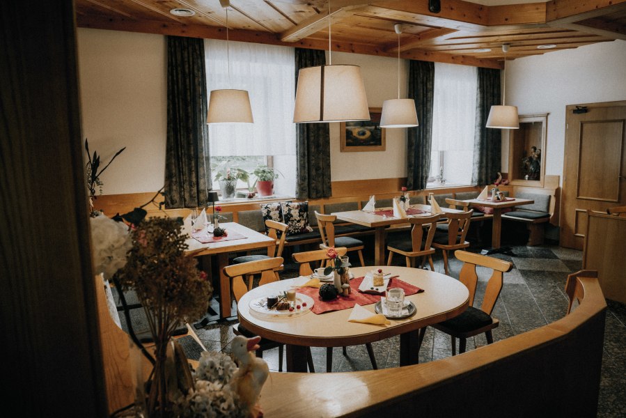 Gem&uuml;tlicher Gastraum mit Holzm&ouml;beln, gedeckten Tischen und H&auml;ngelampen.