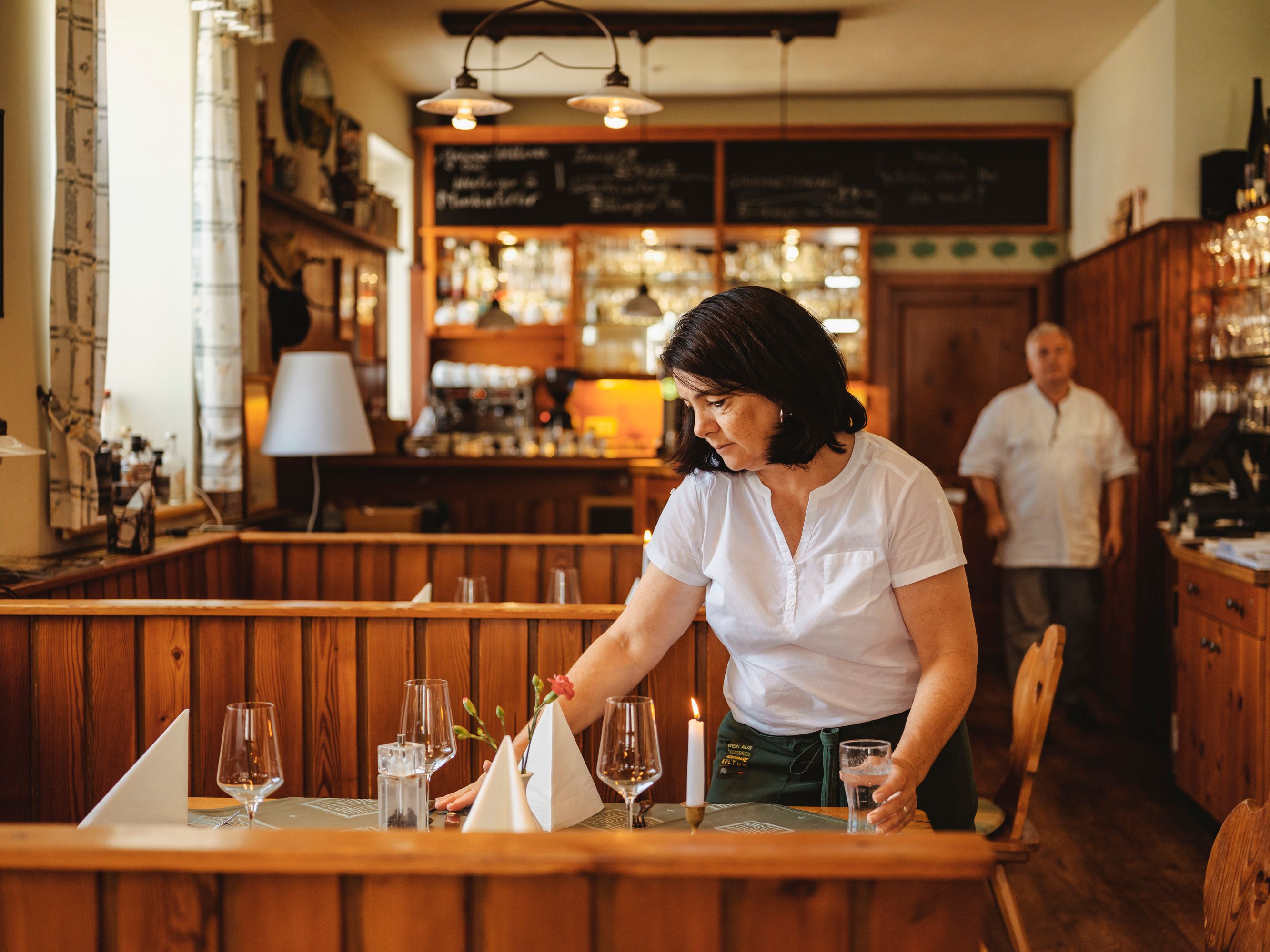 Eine Frau deckt einen Tisch in einem gemütlichen Restaurant.