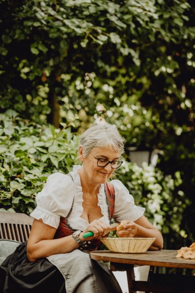 Frau in traditioneller Kleidung schneidet Pilze im Freien.