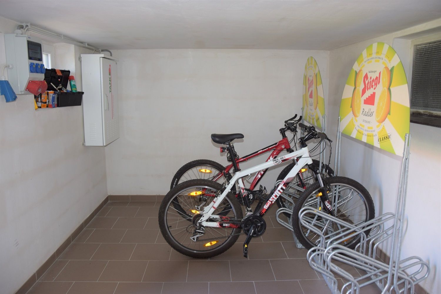 Fahrradraum mit zwei Fahrrädern und Werbeschildern an der Wand.