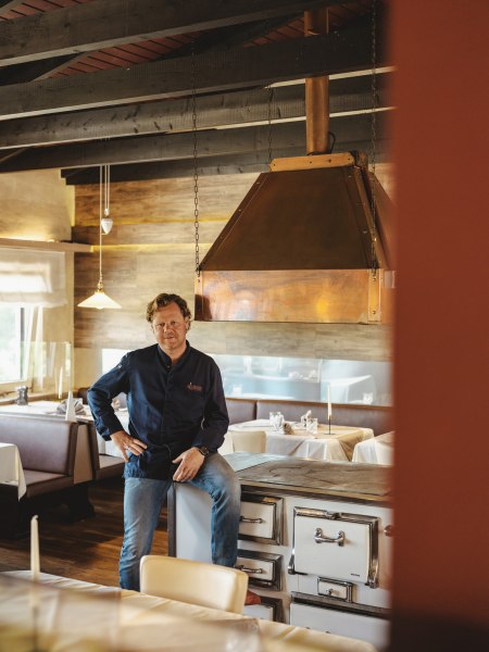 Mann in Restaurant mit rustikalem Holzinterieur und Kupferabzugshaube.