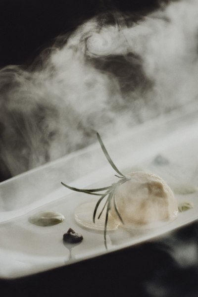 Ein Dessert mit Rosmarin und Rauch auf einem Teller.