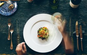 Elegantes Tischgedeck mit Gourmetgericht und Weinglas.