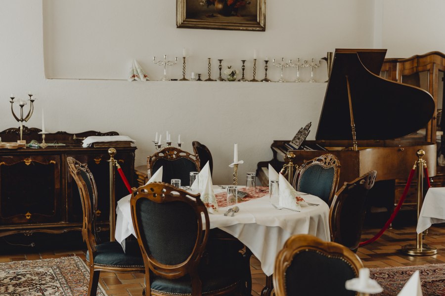 Elegantes Restaurant mit antiken M&ouml;beln, einem Fl&uuml;gel und gedeckten Tischen.