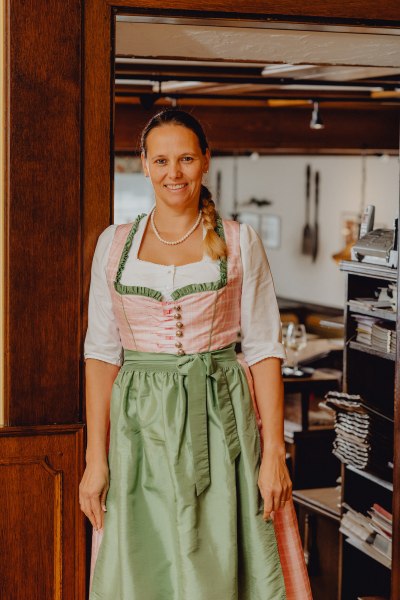 Frau in traditioneller Tracht l&auml;chelt in einem Restaurant.