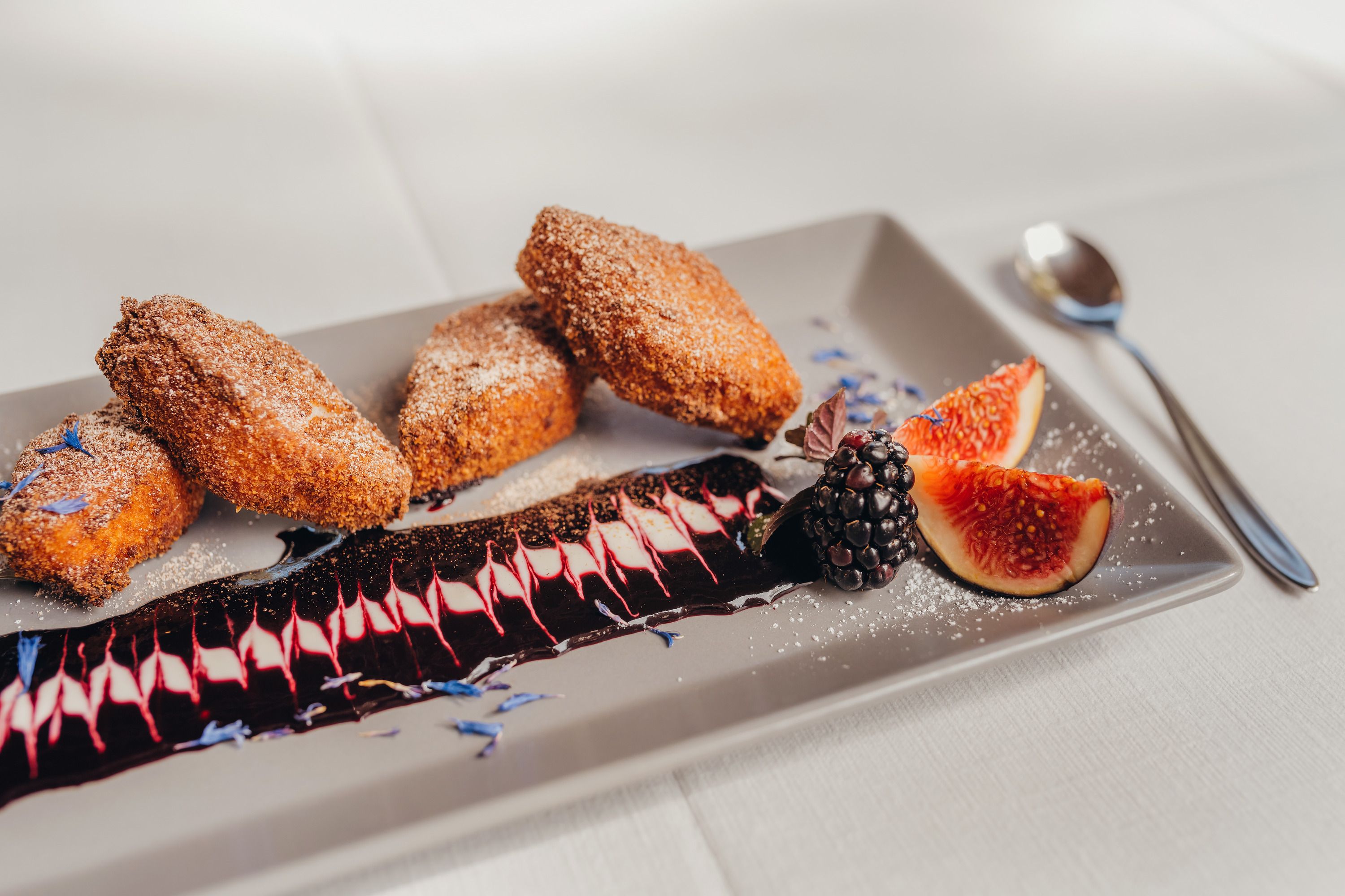 Gebackenes Grieskoch mit Hollersauce, Feigen und Brombeeren auf einem Teller.