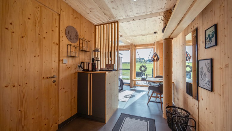 Innenansicht eines modernen Holzhauses mit großen Fenstern und minimalistischer Einrichtung.