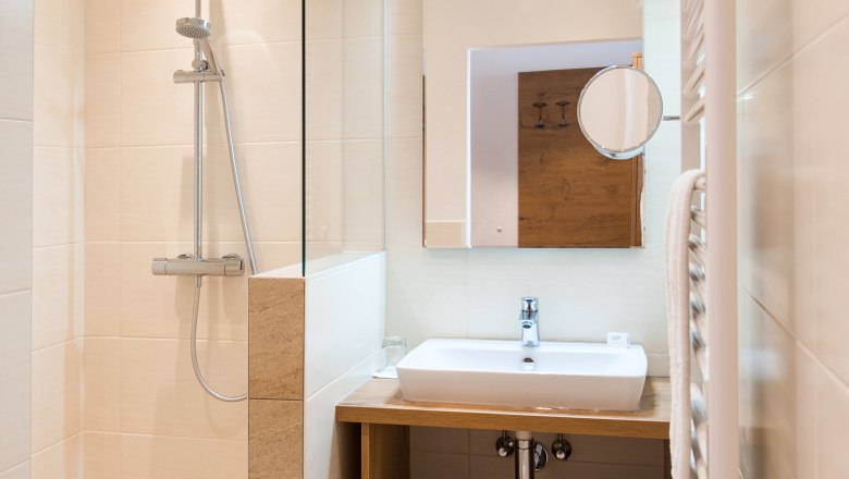 Modernes Badezimmer mit Dusche, Waschbecken und Spiegel.