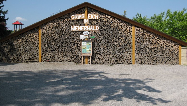 Holzstapel mit Schild 'Griaß Eich im Wienerwald'.