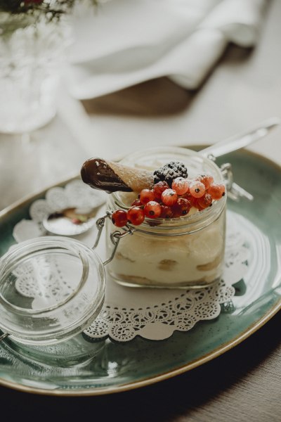 Ein Dessert im Glas mit Beeren und einer Schokoladenwaffel auf einem Teller.