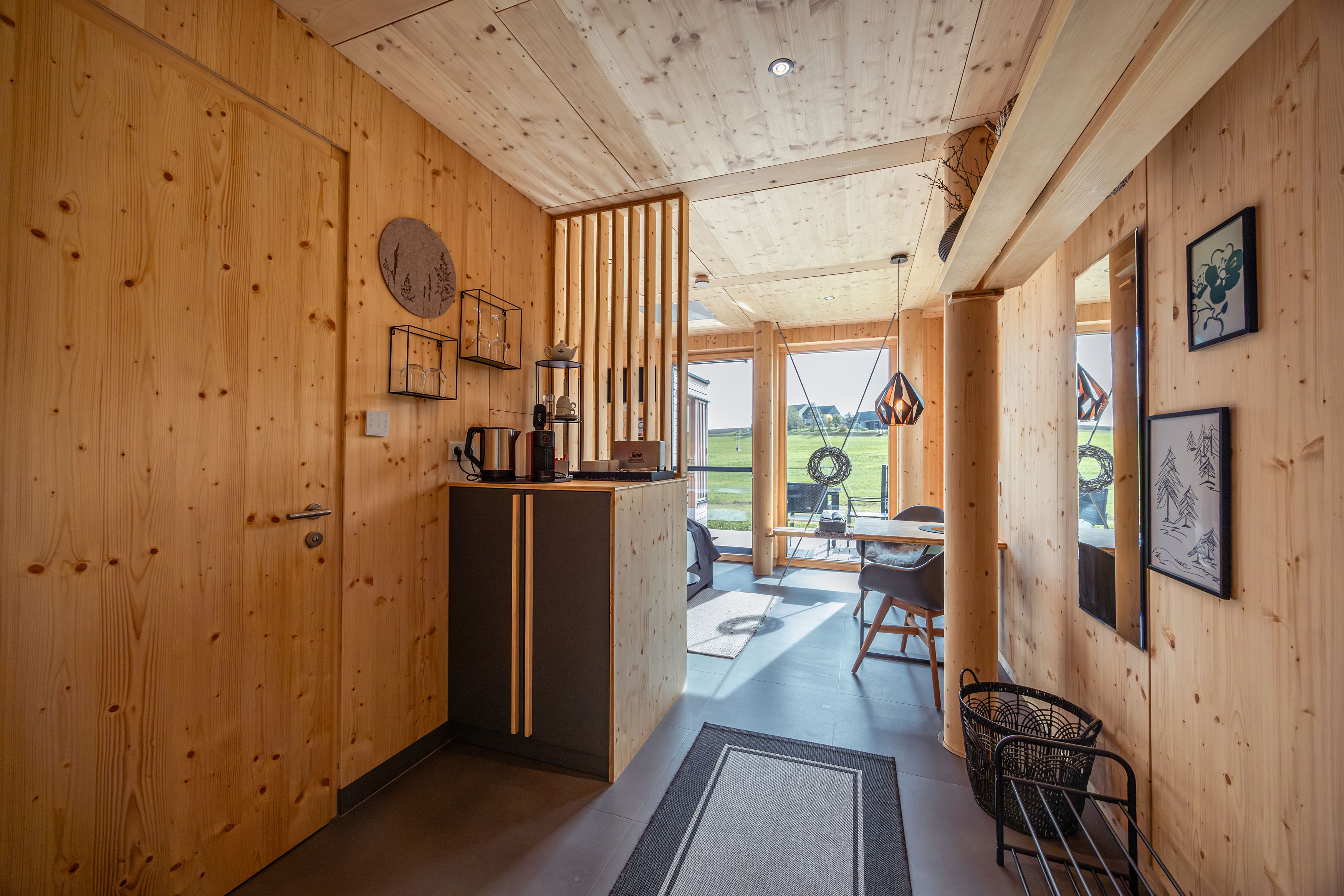 Innenansicht eines modernen Holzhauses mit großen Fenstern und minimalistischer Einrichtung.