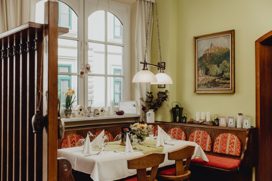 Gem&uuml;tliche Gaststube mit gedecktem Tisch, Holzm&ouml;beln und Dekorationen.