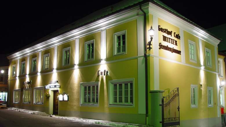 Nachtaufnahme eines gelben Geb&auml;udes mit der Aufschrift 'Gasthof Caf&eacute; Mitter'.