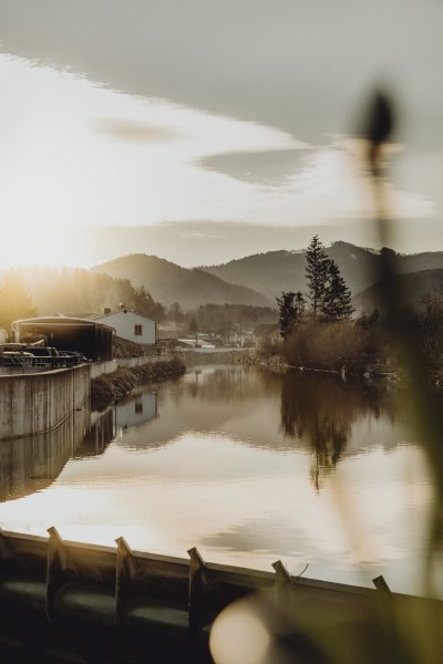 Fluss mit Spiegelung der Landschaft im Sonnenuntergang.