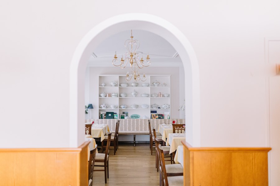 Innenansicht eines traditionellen Wirtshauses mit gedeckten Tischen und einem Kronleuchter.