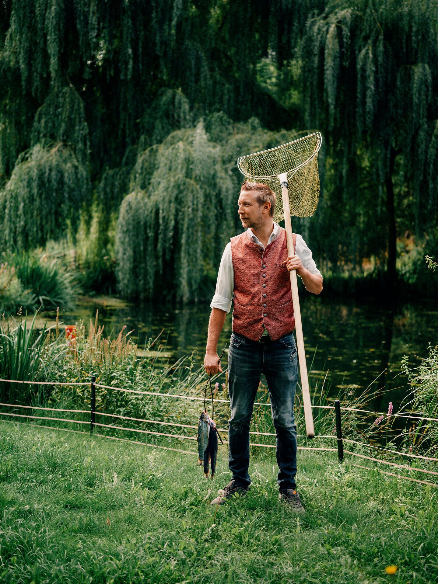 Inmitten der malerischen Landschaft der Wiener Alpen hält ein Wirt stolz seinen Fang in der Hand. Die sanften Wellen des Wassers spiegeln die üppige Vegetation wider und laden dazu ein, die Ruhe und Schönheit der Natur zu genießen.