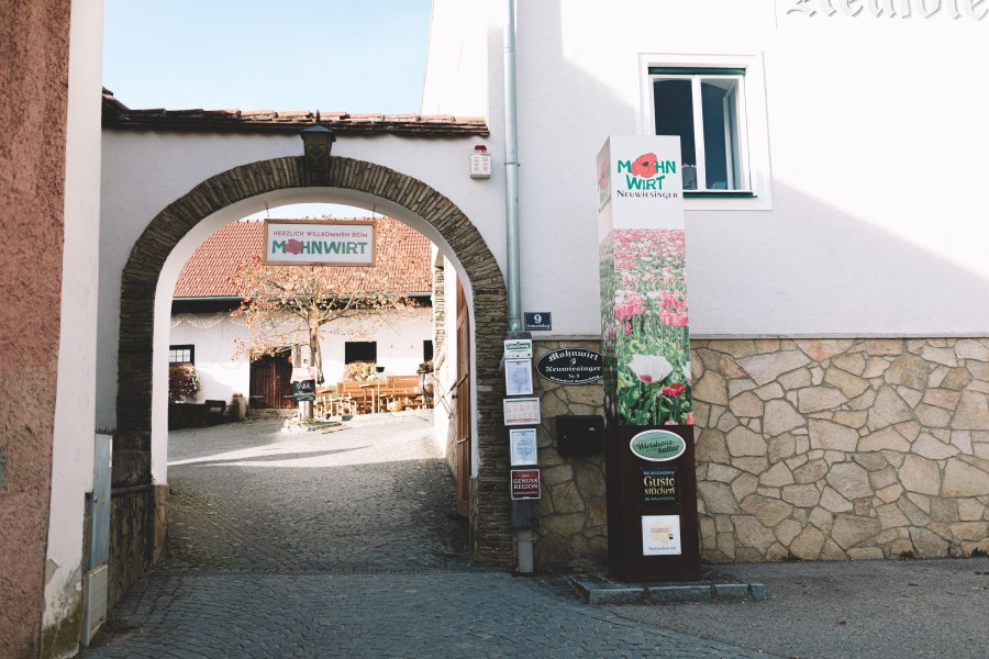 Eingang zum Mohnwirt in Armschlag mit Schild und dekorativem Torbogen.
