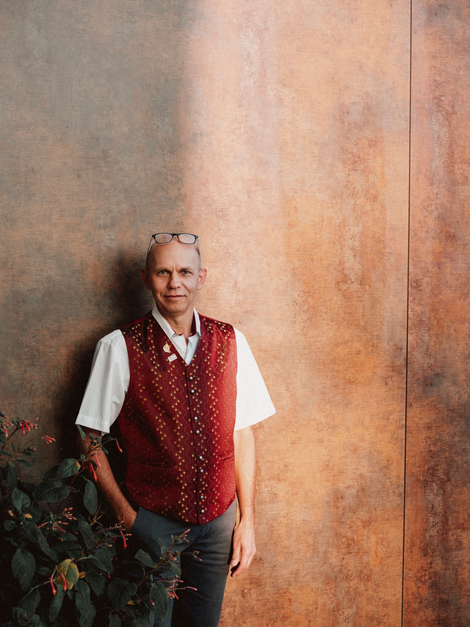 Ein Mann in traditioneller Weste lehnt an einer Wand.